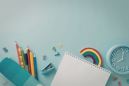 A collection of colorful school supplies, including pencils, a notebook, and a clock, arranged on a...