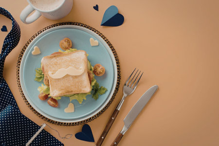A square piece of toast on a blue plate with lettuce, tomatoes, and cheese, accompanied by a fork and knife.の写真素材