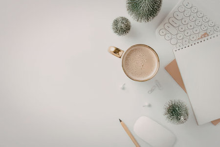 A flat lay of a workspace with a cup of coffee, a notebook, a pencil, and small plants on a white surface.の写真素材