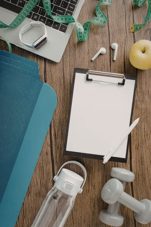 A collection of fitness planning tools and accessories on a wooden deskの写真素材