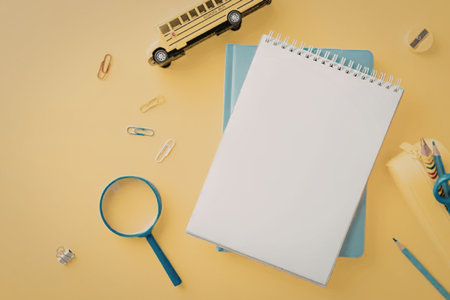 A notebook, pencils, and other school supplies on a yellow background