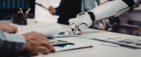 Robot hand and human hand collaborate on data analysis project in a modern office workspace with...