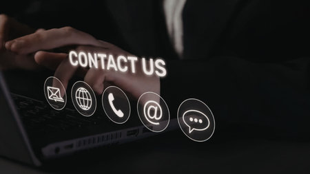Business professional typing on laptop with contact us icons displayed on screen, symbolizing communication and customer support in a digital business environment.の写真素材