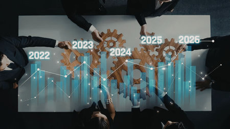 Business professionals gather around a table surrounded by a futuristic graph and interlocking...