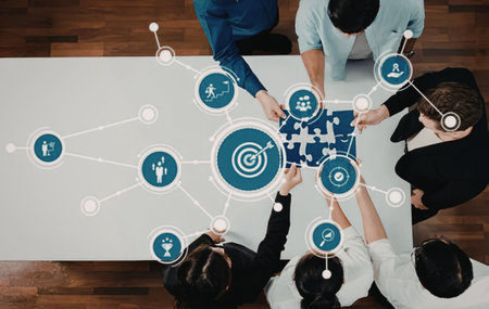 Group of people assembling puzzle pieces with target icons and graphics on a white table symbolizing...