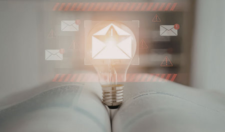 Glowing light bulb on an open book signifies a burst of creative idea and innovative thinking amidst digital communication symbols representing messages and notifications.の写真素材