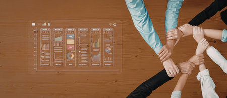 Diverse businesspeople stack hands together in a gesture of teamwork and unity over a wooden table...