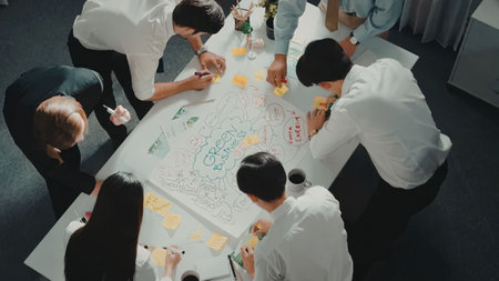 Group of diverse professionals gathered around a large white table, collaboratively brainstorming...