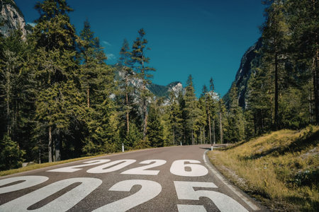 Empty scenic mountain road with the numbers 2025 and 2026 painted on the asphalt surrounded by trees...