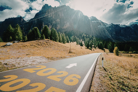 Empty road winding through the mountains with 2026 painted on asphalt, symbolizing journey towards...