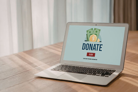 Laptop computer displaying a donation website on its screen with a money illustration and a...