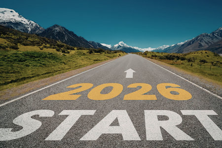 Road with start 2026 painted on asphalt, surrounded by green hills and snow-capped mountains under a...