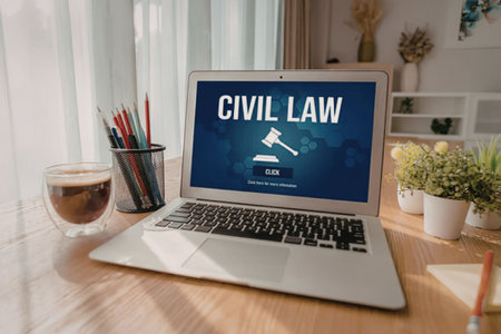 Laptop on wooden desk displays civil law webpage with gavel icon, surrounded by office supplies,...