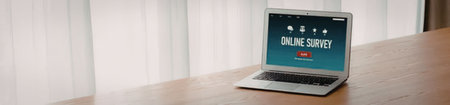Laptop computer on wooden table displays online survey on its screen near white curtains in a modern...