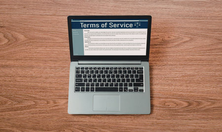 Laptop open on a wooden table displaying terms of service agreement on its screen with a blue header and white text area.の写真素材