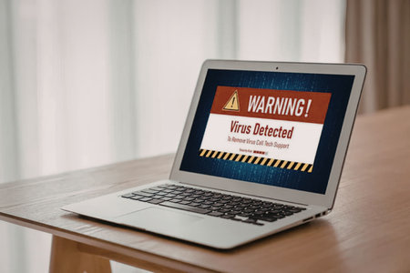 Laptop on a wooden table shows a virus detected warning message on its screen with a red alert...