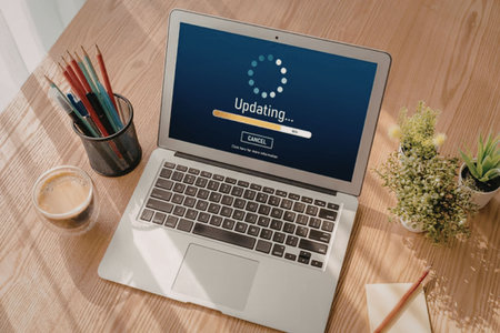 Laptop screen shows software update in progress on a wooden desk surrounded by office supplies and...