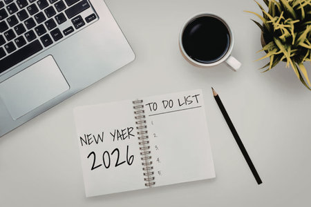 New year 2026 to do list notebook lies next to a laptop and a cup of coffee on a clean white...