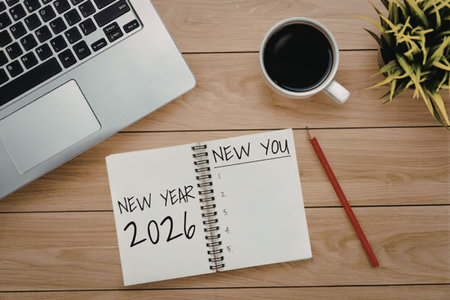 Notebook on wooden desk displays new year 2026 and new you with laptop and coffee nearby symbolizing...