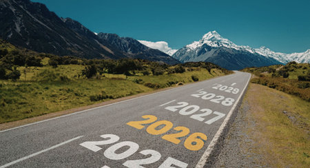 Open road stretches forward with years 2025 to 2029 painted on the asphalt, symbolizing journey through time and progress toward the future in a scenic mountain landscape.の写真素材