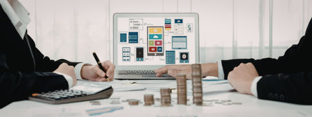 Two business professionals in suits collaborate on a financial project using a laptop and reviewing...