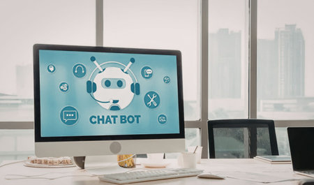 Computer monitor on office desk displays chatbot interface with customer service icons and robot...