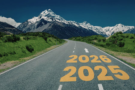 Empty road stretching towards snowy mountains with 2025 and 2026 painted on asphalt symbolizing...