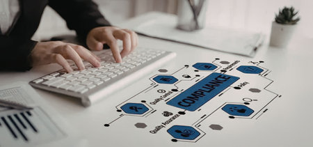 Business professional typing on laptop while reviewing a compliance flowchart diagram on a modern...