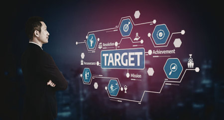 a man in a black suit is standing with his arms crossed, looking at a futuristic interface with a pink and purple glow. The interface features a large blue and white 'TARGET' sign surrounded by various blue hexagons with white icons and small white text labels. The background is dark with a cityscape visible in the distance.の写真素材
