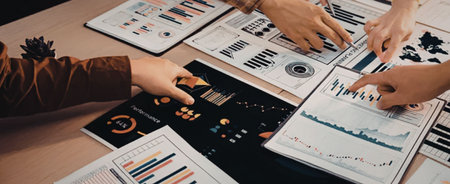 Business professionals collaboratively analyze financial data, marketing reports, and performance...