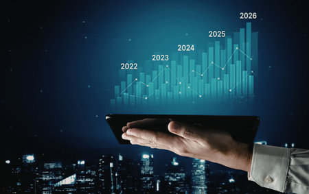 Business professional holds tablet displaying projected growth graph above cityscape at night...