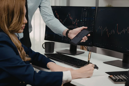 Business professionals collaborate analyzing stock market trends on multiple computer screens with...