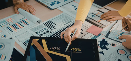 Business team collaborating over data analysis on tablet surrounded by various financial charts and...