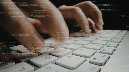 Person's hands typing on a white keyboard with lines of code overlaid on the image symbolizing...