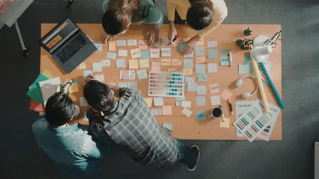 Four young professionals gather around a table to brainstorm and collaborate on a creative project...