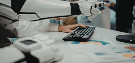 Robotic arm and human hand collaborate on a computer task with charts and graphs scattered across...
