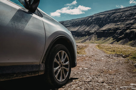 a silver car is parked on a rocky road in the mountains