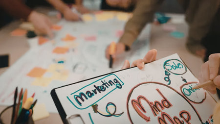 A close-up of hands holding a notebook with a marketing mind map and colorful sticky notes on a table.