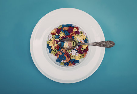 Bright and colorful alphabet cereal in a white bowl with spoon on blue background