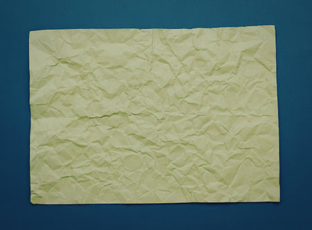 Close-up of crumpled yellow paper on a blue background