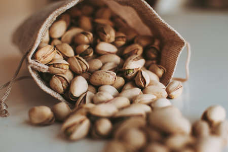 Large handful of beautiful pistachios in a cloth bag on the table.の写真素材