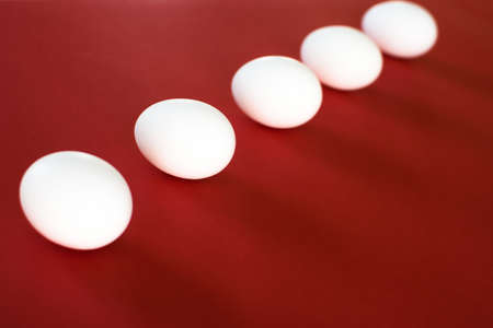 Five easter white eggs on red background.