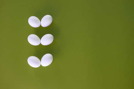 Six easter white eggs on green background.