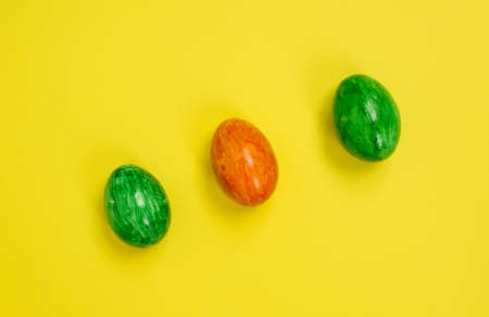Three orange and green easter eggs on a yellow