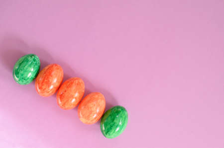 Orange and green easter eggs on violet