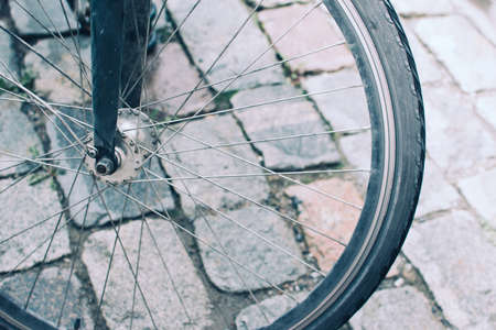 Close wheel axle of a bicycle on a background of brick pavement.