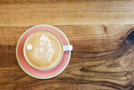 One cup of cappuccino in pastel colors on a wooden surface. Flatlay.