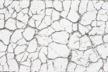 White old cracked paint, cracked by the heat in the sun, on the concrete surface. Great for design...