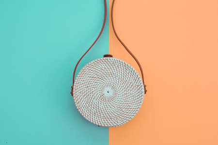 Beautiful round straw handbag on the orange-green background. Trendy handbag. の写真素材