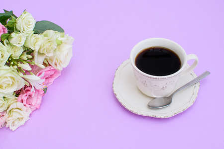 Colorful beautiful bouquet of different fresh flowers and cup of black coffee on the purple background. Top view.の写真素材